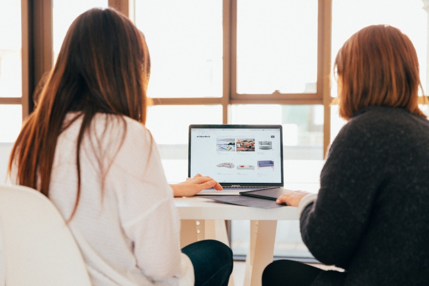 two people looking at computer in front of window